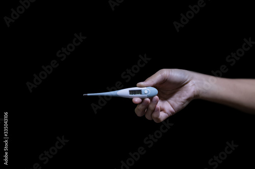 Hand holding Digital thermometer on a black background. Medical thermometer display 38.1 degrees celsius. Concept Check fever covid19 or coronavirus..