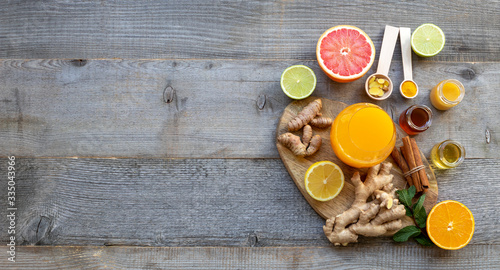 Top view on the immune system booster - orange juice, ginger, turmeric, citruses, and honey on the old wooden table