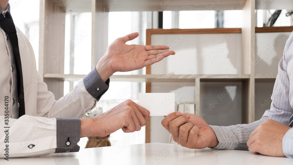 Closeup of man giving white business card to another man.