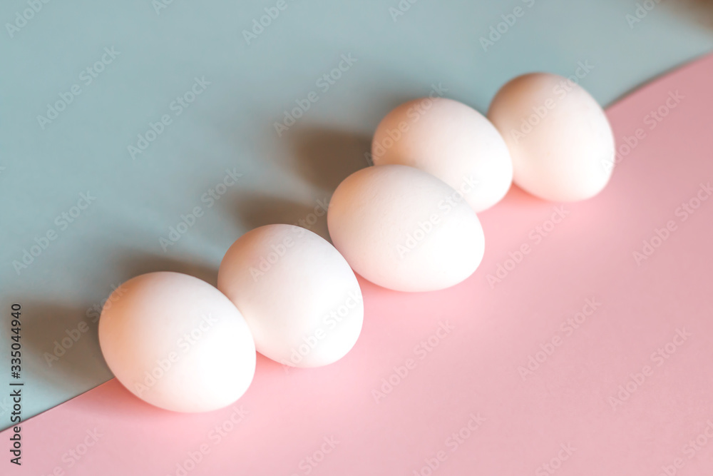 Chicken eggs on a blue and pink background.