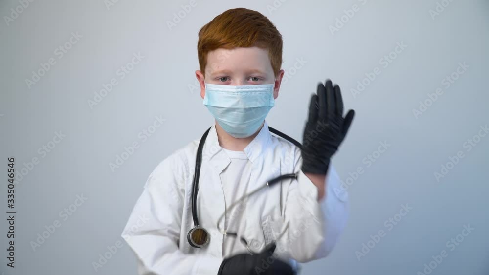 Close up of caucasian littile doctor with a stethoscope in protective mask. Littile doctor puts on black protective gloves Close up of caucasian littile doctor with a stethoscope in protective mask. Littile doctor puts on black protective gloves