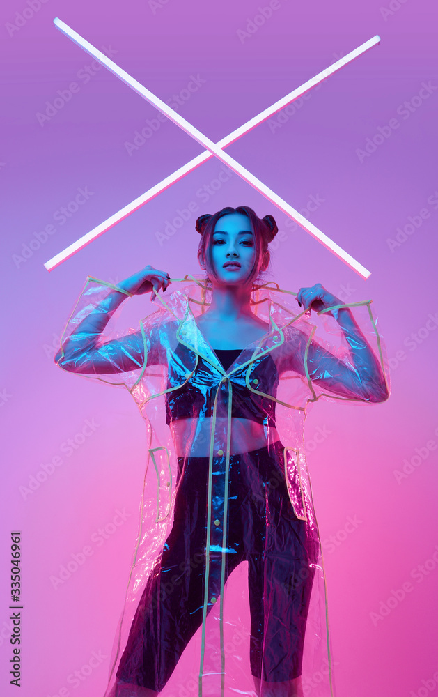 Elegant beautiful woman in a raincoat around colourful bright neon Elegant beautiful woman in a raincoat around colourful bright neon