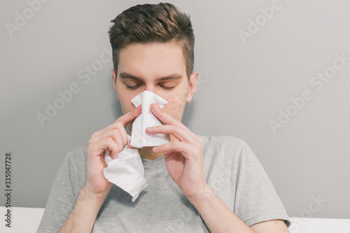 White man gets sick and blows his nose into a white napkin photo