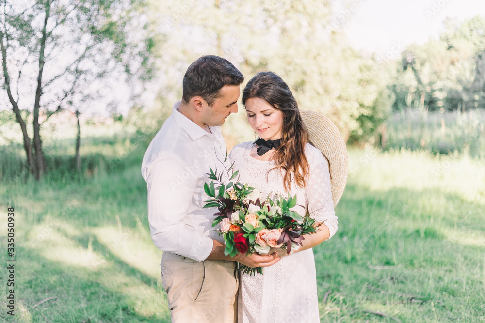 Naklejka premium Happy bride and groom posing in the woods against the backdrop of a wooden cottage. Wedding in a vintage Boho style.