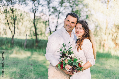 Wedding in a vintage Boho style.Happy bride and groom posing in the woods against the backdrop of a wooden cottage.