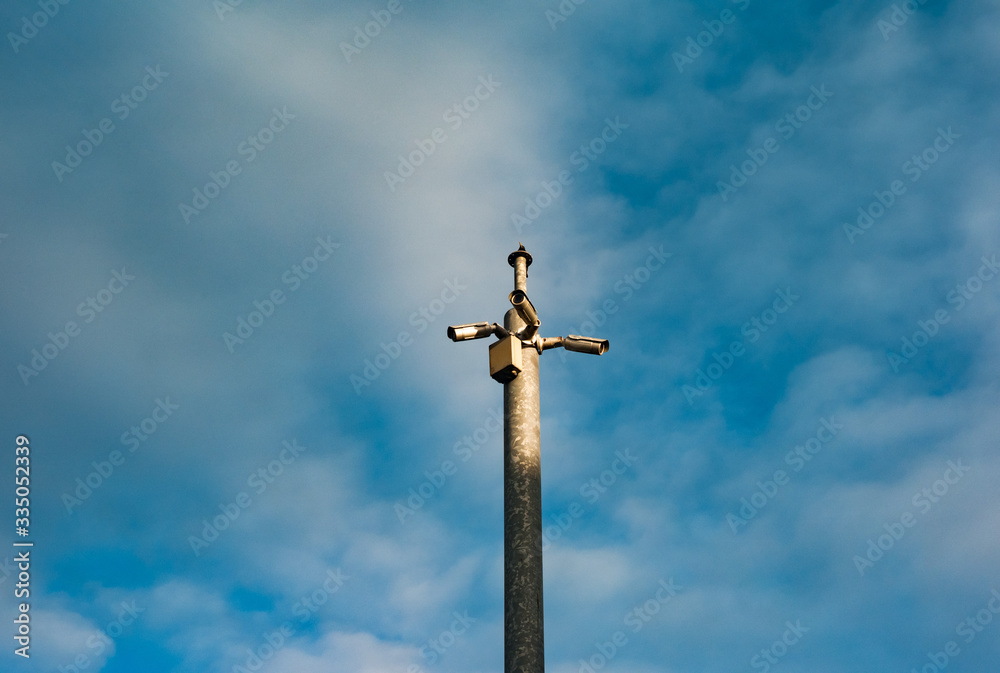 CCTV cameras on a metal pole overlooking streets, cloud sky background CCTV cameras on a metal pole overlooking streets, cloud sky background