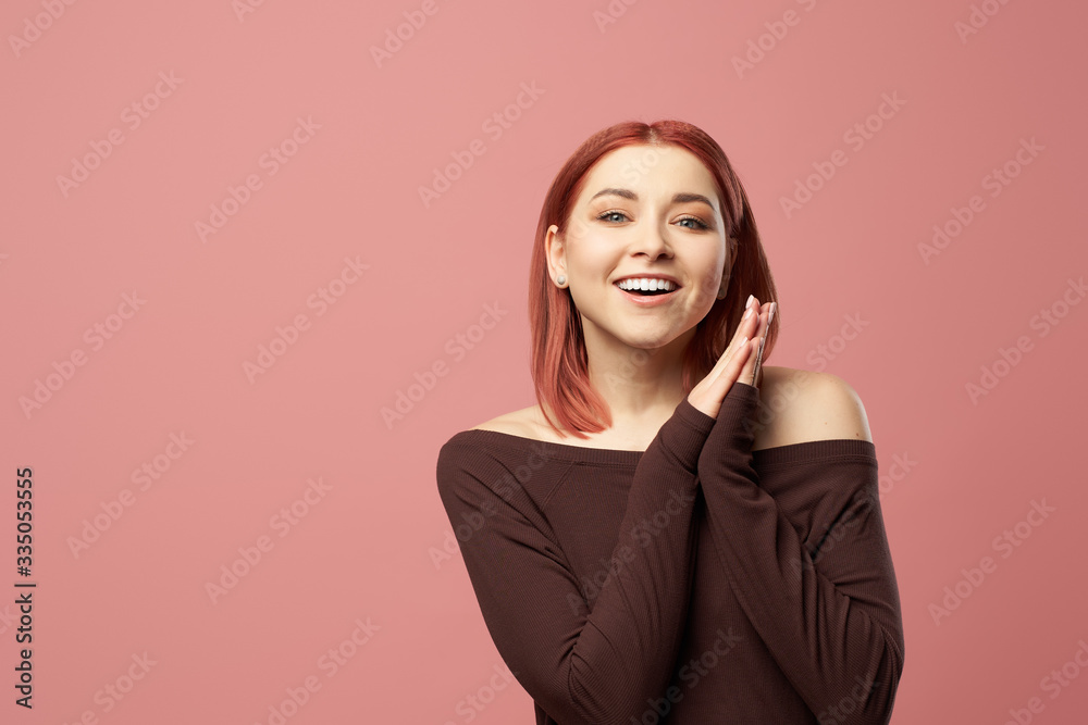 Smiling ginger girl in burgundy sweater isolated on empty pink background Smiling ginger girl in burgundy sweater isolated on empty pink background