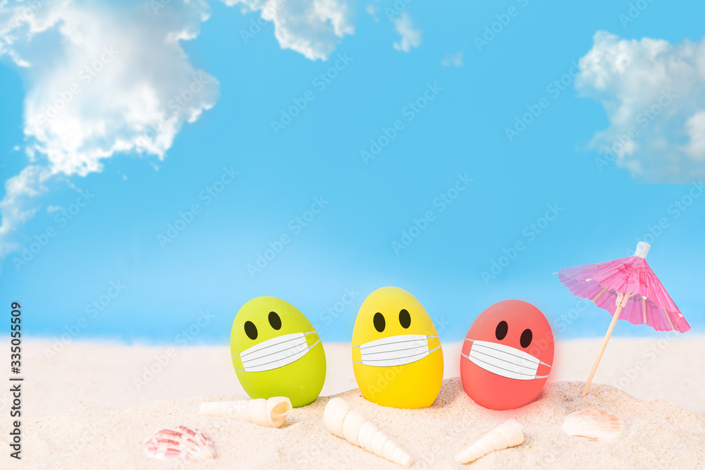 Obraz premium colorful eggs wear fabric mask on white sand beach over cloudy sky background, image for happy Easter or Happy weekend concept.
