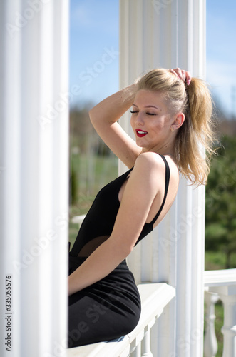 Young beautiful woman. Blonde posing railing. Red lipstick on the lips. Photo of a model in nature.