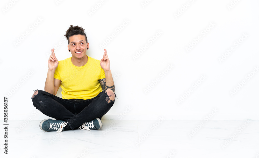Caucasian man sitting on the floor with fingers crossing and wishing the best Caucasian man sitting on the floor with fingers crossing and wishing the best