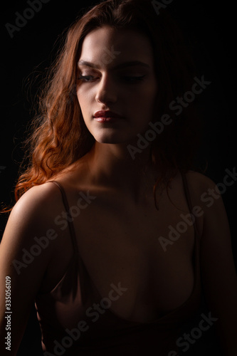 Portrait of a young curly girl in a dark studio