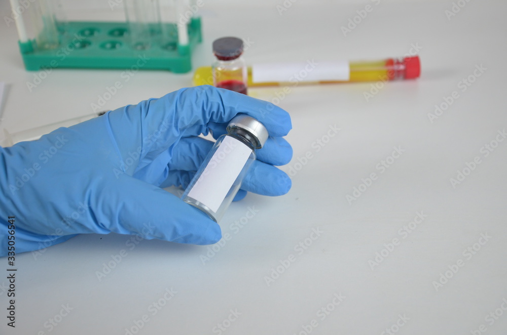 Doctor, nurse or scientist hand in blue nitrile gloves holding flu, measles, coronavirus (COVID-19) vaccine shot for baby and adult vaccination, medicine and drug concept Doctor, nurse or scientist hand in blue nitrile gloves holding flu, measles, coronavirus (COVID-19) vaccine shot for baby and adult vaccination, medicine and drug concept