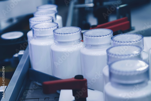 white plastic bottle on the production line of the conveyor at filling machine in the medical factory. selective focus. photo