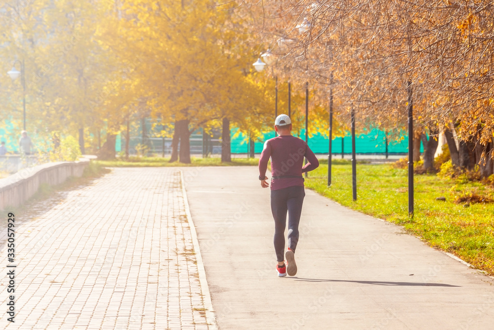 Obraz premium A man runs through the park on an autumn sunny day