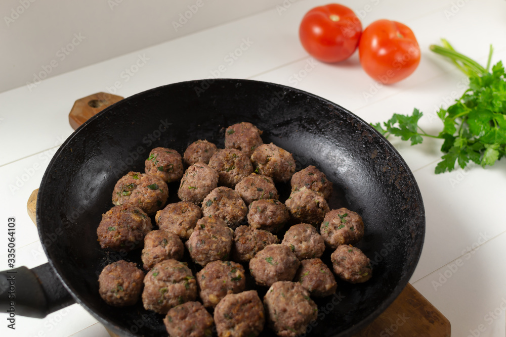 Homemade fried meatballs with herbs in a pan on a white background. Swedish traditional cuisine.