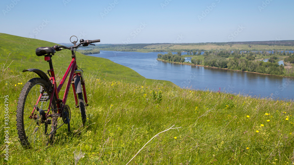 mountain bike on the high bank of the river Kama, view of the river Kama and water meadows