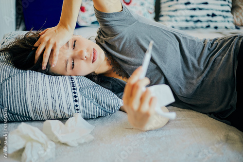 Sick woman lying in bed with cold, flu and high fever.