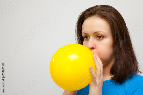 beautiful woman is blowing up a yellow balloon