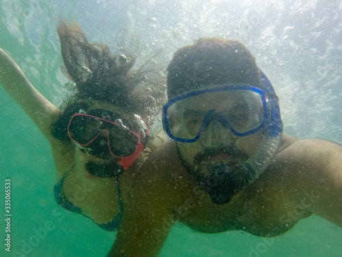 casal mergulhando de máscara e snorkel no mar