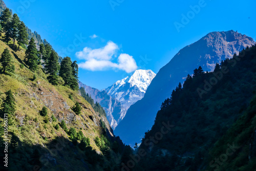 View on Himalayas  Annapurna Circuit Trek  Nepal. Early morning in the mountains. Lower parts of the mountains covered in shadow  high snow caped mountains peaks catching the first beams of sunlight