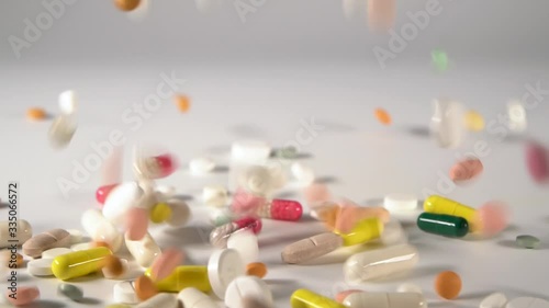 Many multicolored tablets fall on the table.A huge number of pills falling on white background top view close up