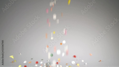 Many multicolored tablets fall on the table.A huge number of pills falling on white background slow motion