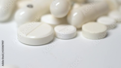 Huge number of pills falling on white background  slow motion.Many white pills