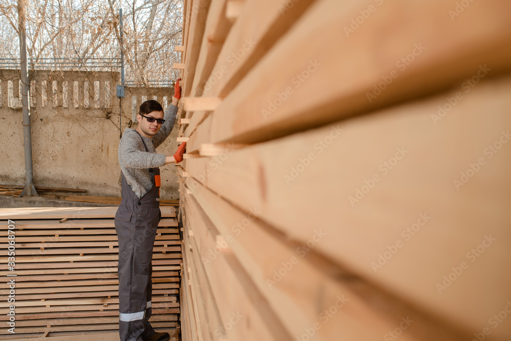 Lateral view of young man carpenter at the wooden warehouse