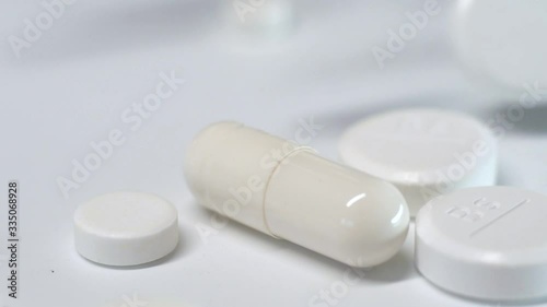 Many white pills falling white background.Macro