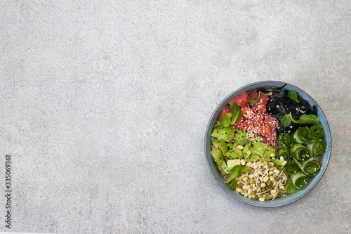 Poke bowl with rice, avocado, pickled cucumber and crispy sea kale.