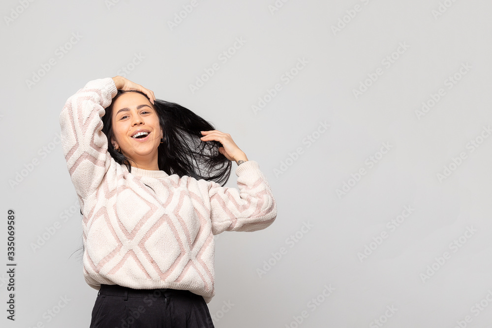 Portrait of a young beautiful cute brunette girl in a warm winter sweater on light gray background. Portrait of a young beautiful cute brunette girl in a warm winter sweater on light gray background.