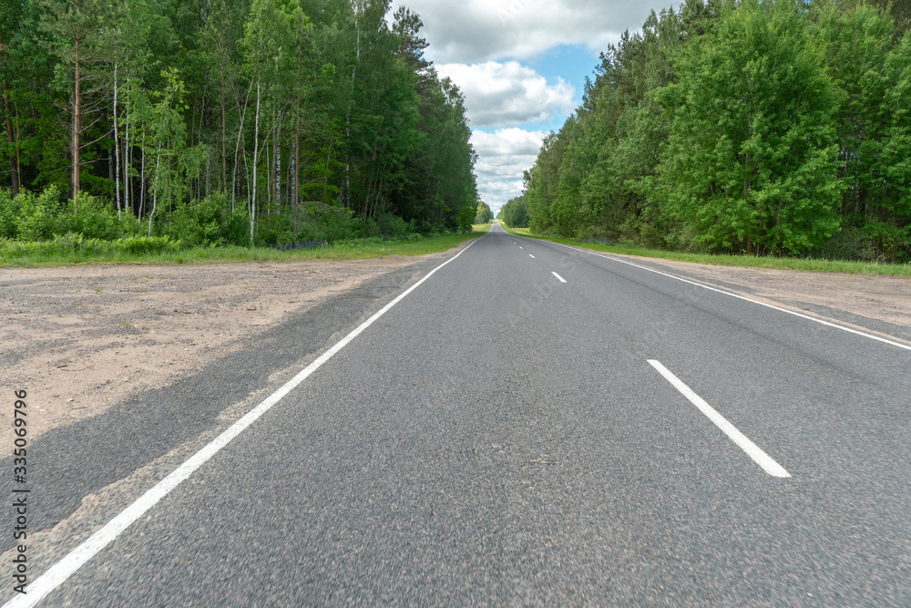 Highway or asphalt road through the forest. An empty roadway with no cars or people. Travel to natural places or reserves. social distance. Absence of people. Coronavirus. COVID19