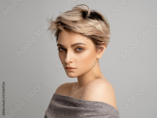 Canvas Print Sexy blonde woman with short hair posing in studio over gray background