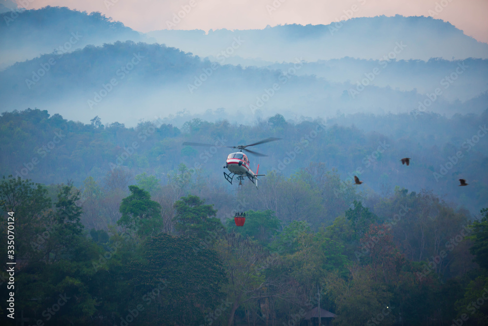 The helicopter is drawing water from the reservoir and will be watered to extinguish the burning forest in the mountains. The helicopter is drawing water from the reservoir and will be watered to extinguish the burning forest in the mountains.