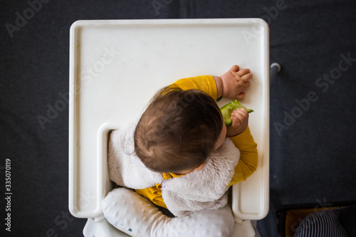 Healthy cute caucasian baby boy have, eat vegan raw supplementary food at home in his highchair. Vegan infant concept. Top above, flat lay view