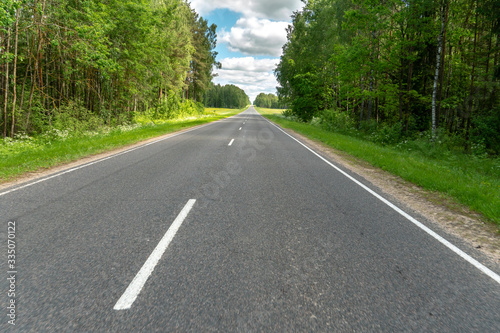 Highway or asphalt road through the forest. An empty roadway with no cars or people. Travel to natural places or reserves. social distance. Absence of people. Coronavirus. COVID19