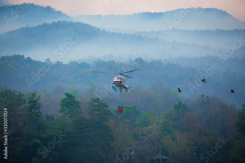 The helicopter is drawing water from the reservoir and will be watered to extinguish the burning forest in the mountains.