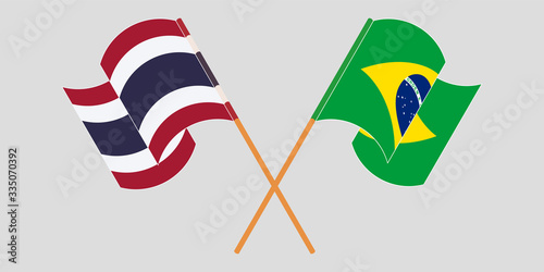 Crossed and waving flags of Brazil and Thailand