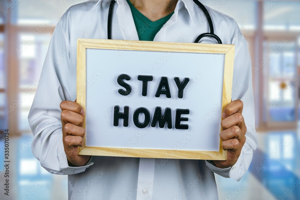male doctor with blackboard with inscription stay home on a blurred medical background male doctor with blackboard with inscription stay home on a blurred medical background
