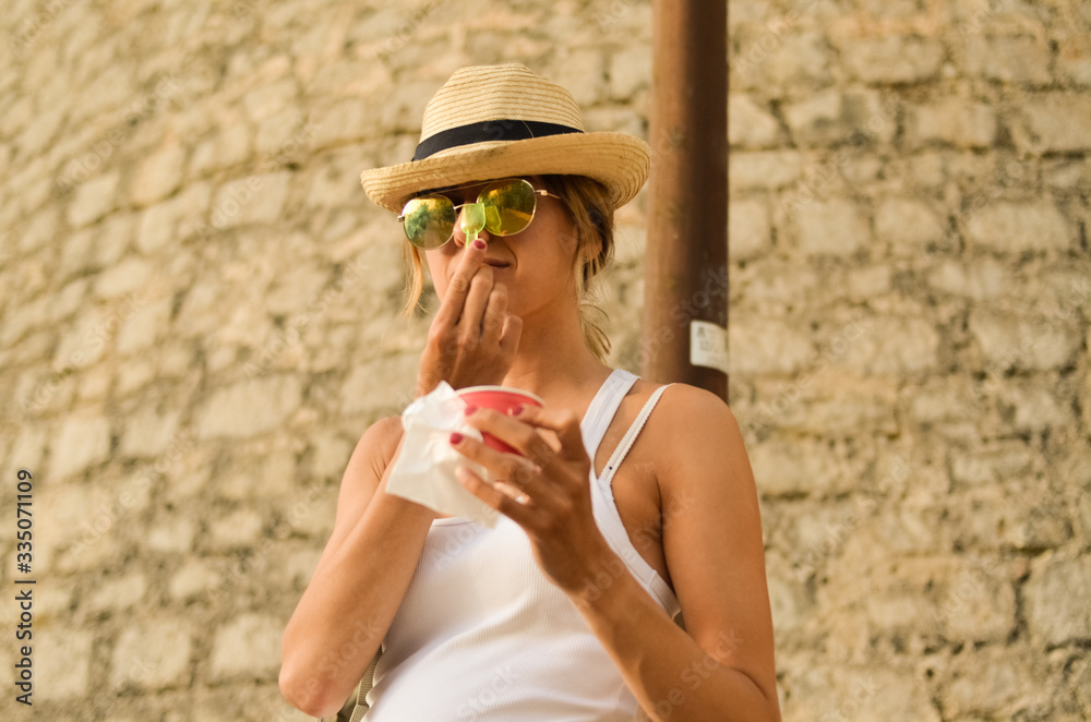 White woman with Straw hat and sunglasses tasting an ice-cream in Ibiza afternoon