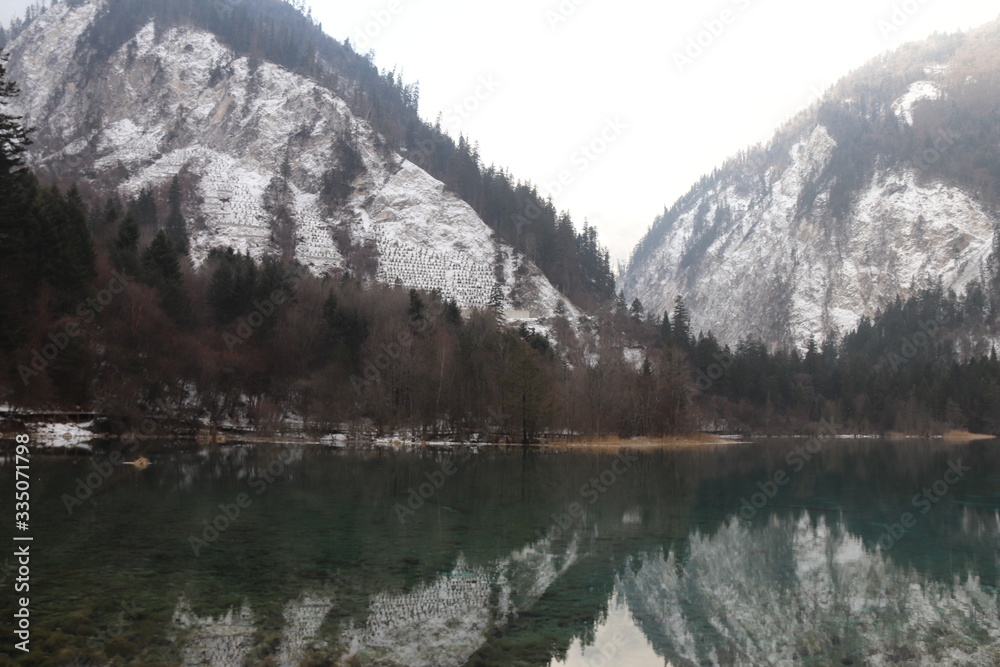 beautiful landscape of a lake in national park, Sichuan China with snow and reflection of the trees in the water