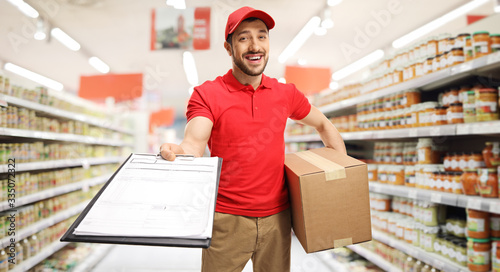 Delivery man with a box and clipboard with a document in a supermarket