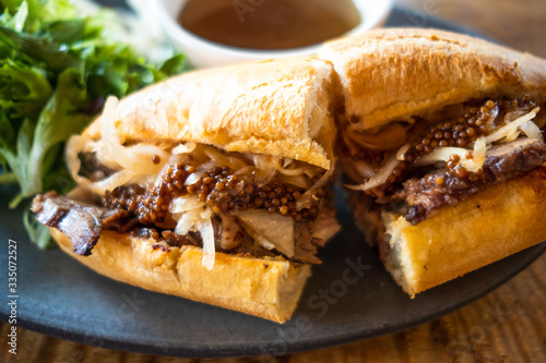 Pork sandwich with carmelized onion and whole mustard, au jus dipping sauce in back