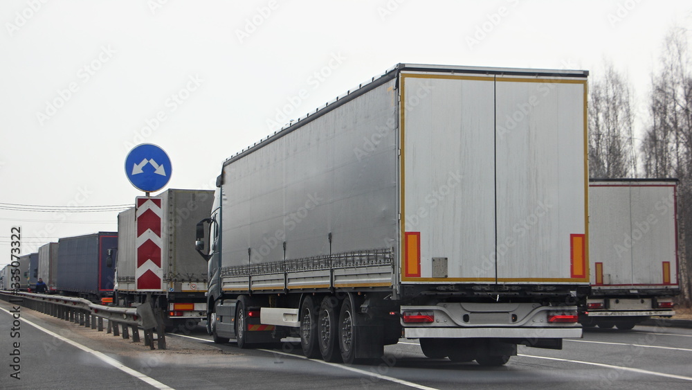 A many semi trucks queue on control point at spring dayback view, international cargo delivery traffic problem, illustration concept A many semi trucks queue on control point at spring dayback view, international cargo delivery traffic problem, illustration concept