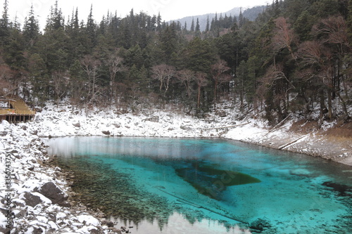 beautiful landscape of a lake in Jiuzhaigou national park, Sichuan China with snow and reflection of the trees in the water