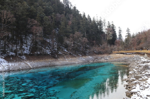 beautiful landscape of a lake in Jiuzhaigou national park, Sichuan China with snow and reflection of the trees in the water