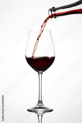 Silhouette of a wine glass, wine and grape juice is poured from a bottle, against a white background with reflection in Zurich, Europe, Switzerland.