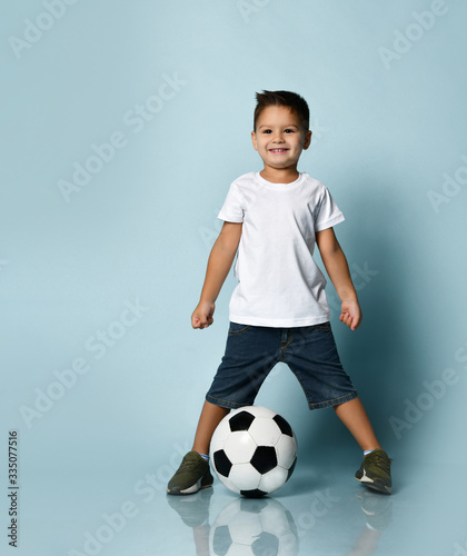 Cute boy playing football, happy child, young male teen goalkeeper enjoying sport game, holding ball, isolated portrait of a preteen smiling and having fun