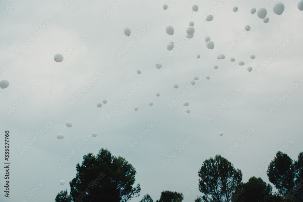 Muchos globos blancos volando por el cielo con arboles Stock Photo