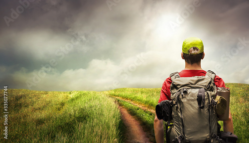 Young man hiking a path leading to the horizon on the open countryside  with dramatic sky and light mood